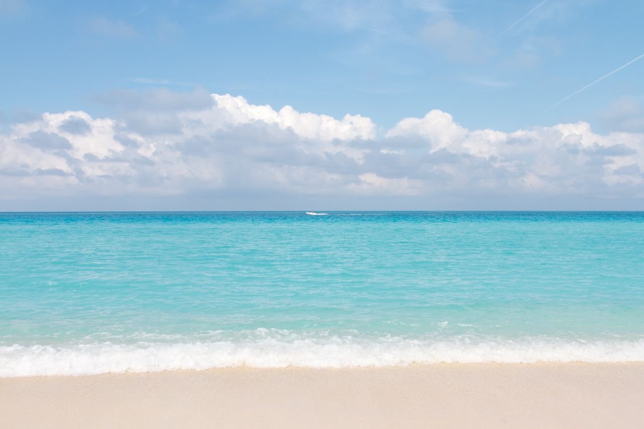 The Art of Drawing Readers In: Your attractive post title goes here A tranquil beach scene featuring clear turquoise waters and a sandy shore under a bright blue sky.